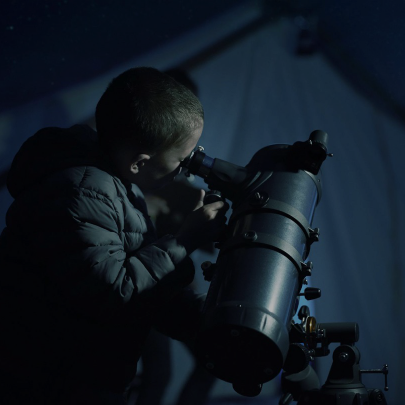 Man looking through a telescope into the night sky.